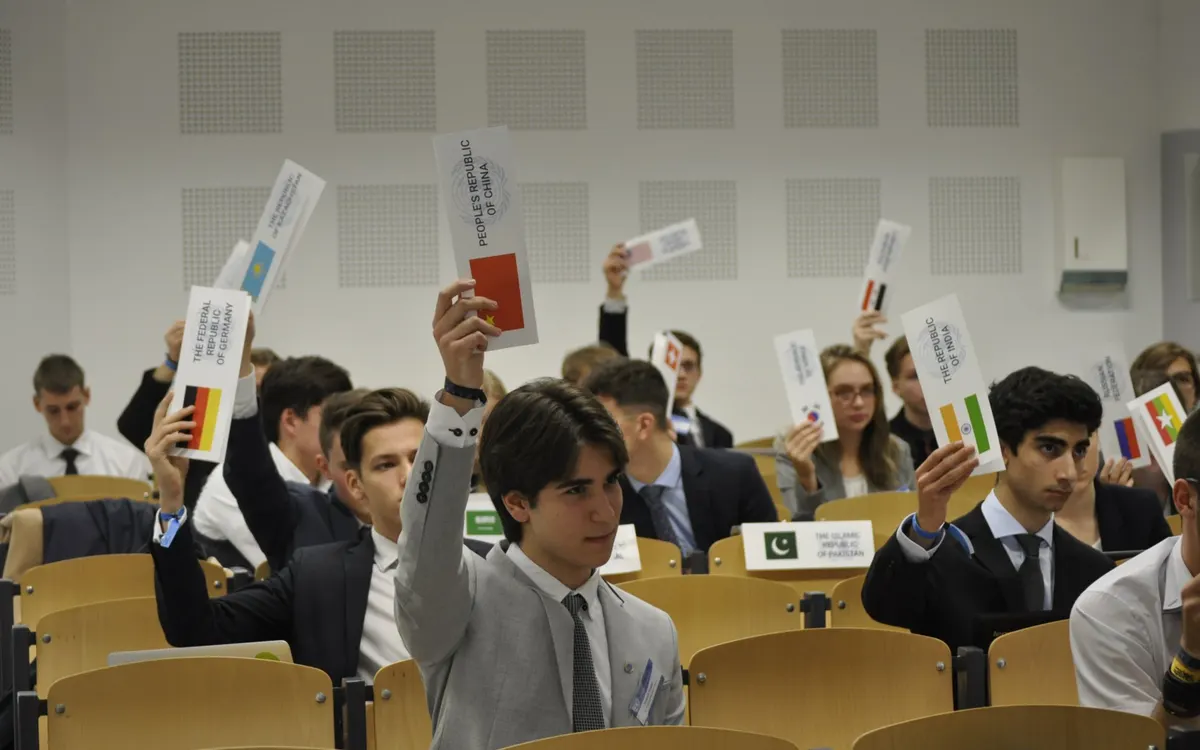 Delegates at Bratislava Model United Nations raising their country placards during a committee vote